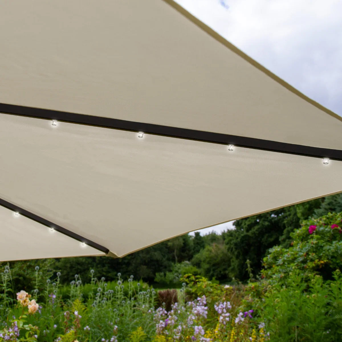 Cream 3m LED cantilever parasol with a sleek design, featuring integrated lights and a sturdy frame, set against a vibrant garden backdrop