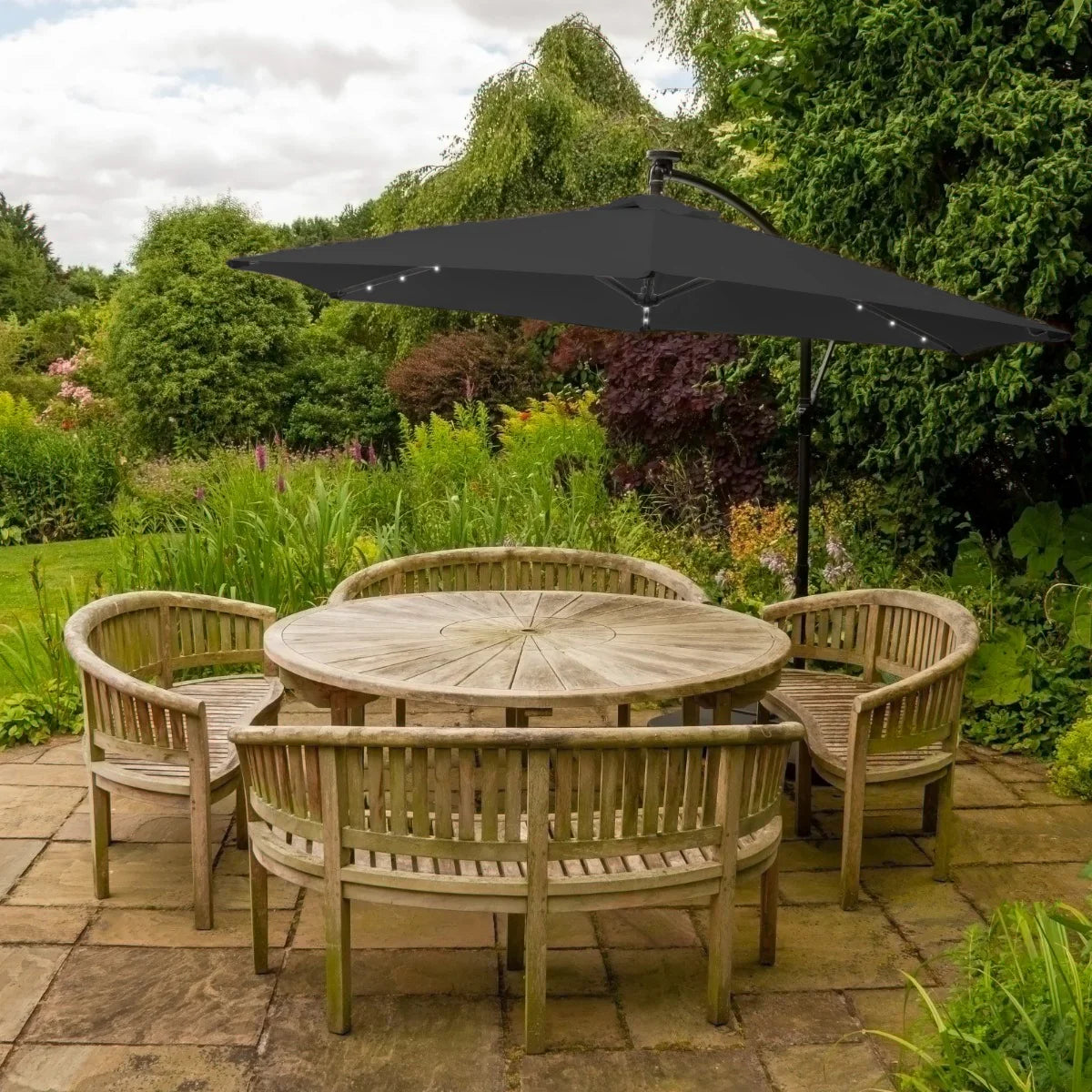 Grey 3m LED cantilever parasol with a sleek design, positioned over a wooden dining table surrounded by rustic chairs in a lush garden setting