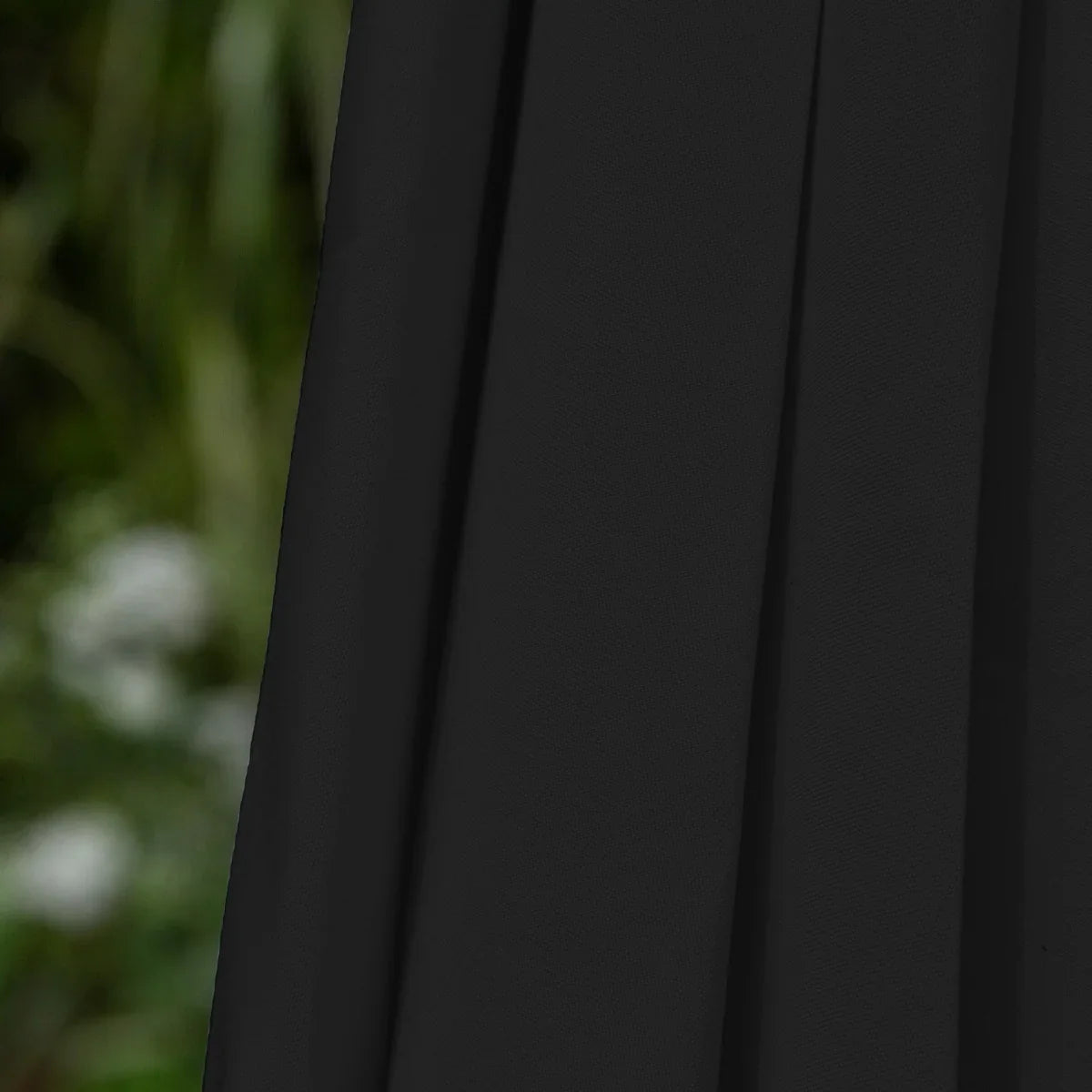 Black 2.7m LED tilt parasol with a sleek, textured fabric, showcasing its elegant drape and modern design against a blurred green background