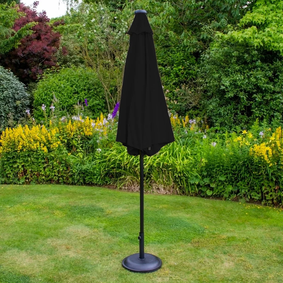Black 2.7m LED tilt parasol with a sleek design, standing on a sturdy base, surrounded by vibrant garden flowers and greenery