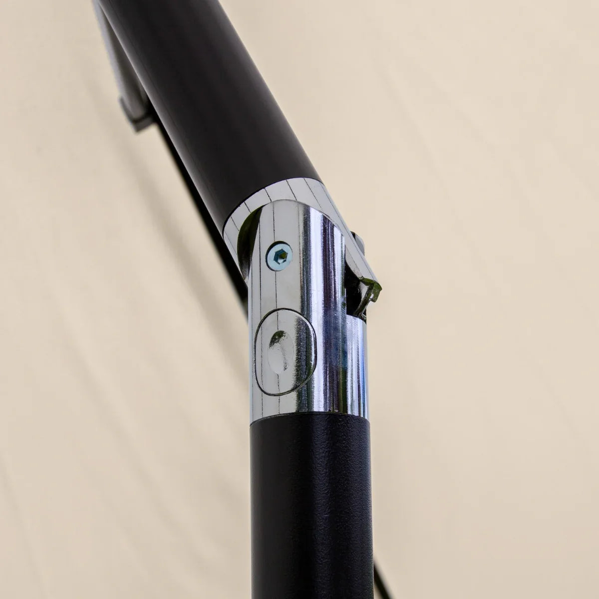 Close-up of the chrome and black metal frame of a beige 2.7m LED tilt parasol, showcasing the adjustable tilt mechanism and sturdy construction