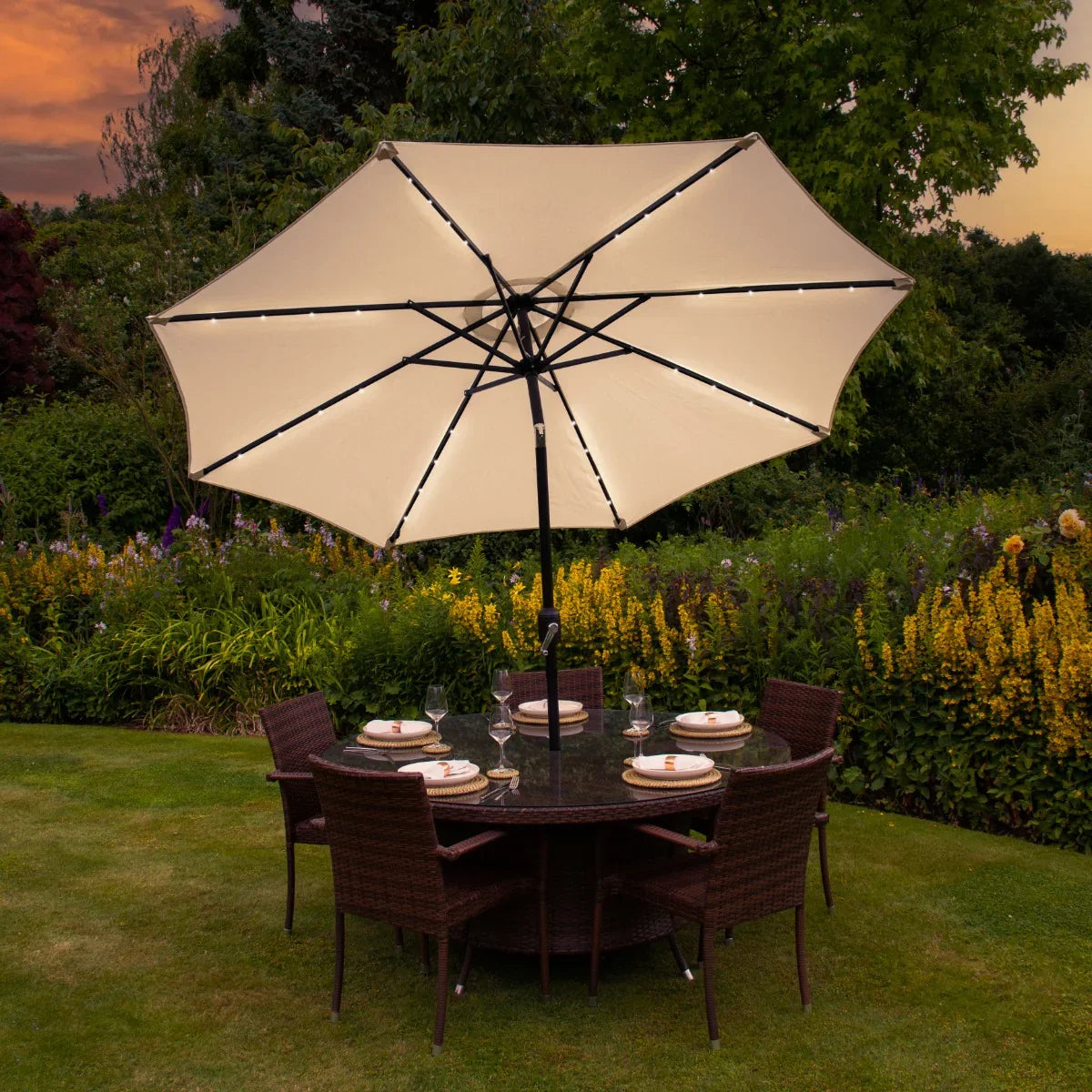 Cream 2.7m LED tilt parasol with a spacious canopy, set over a round dining table surrounded by wicker chairs in a garden setting