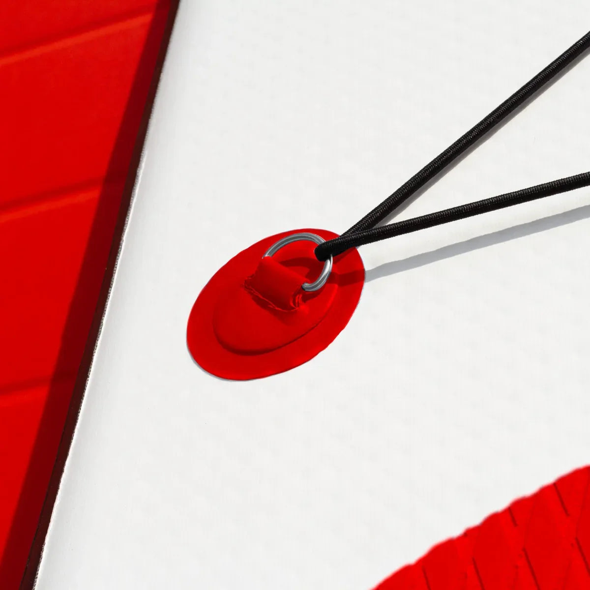 Close-up of a red inflatable paddle board's bungee cord attachment and textured surface, showcasing durability and design...