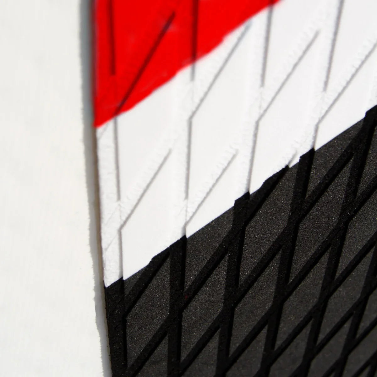 Close-up of the textured surface of a 10ft red inflatable paddle board, featuring black and white accents and a diamond...
