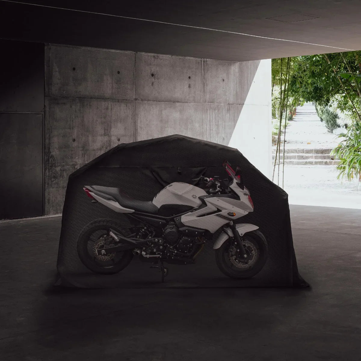 Motorbike tent featuring a sleek, black exterior with a spacious design, showcasing a white motorcycle inside against a modern concrete backdrop