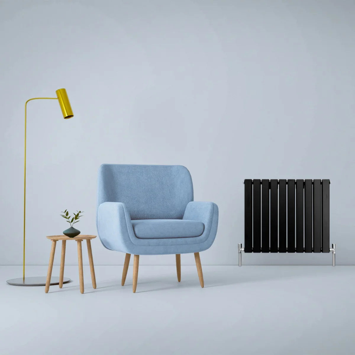 Matte black designer flat panel radiator, 600mm x 700mm, showcased beside a blue armchair and modern decor in a stylish interior setting