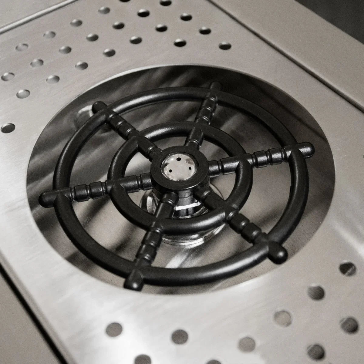 Black cast iron burner grate on a polished stainless steel surface, designed for the Deluxe Cocktail Bar Station, showcasing durability and style