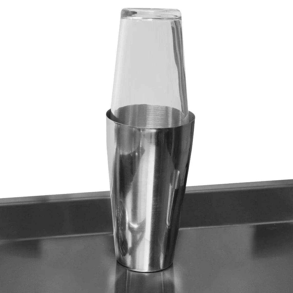 Stainless steel cocktail shaker with a clear glass cup nested inside, showcasing sleek design and polished finish