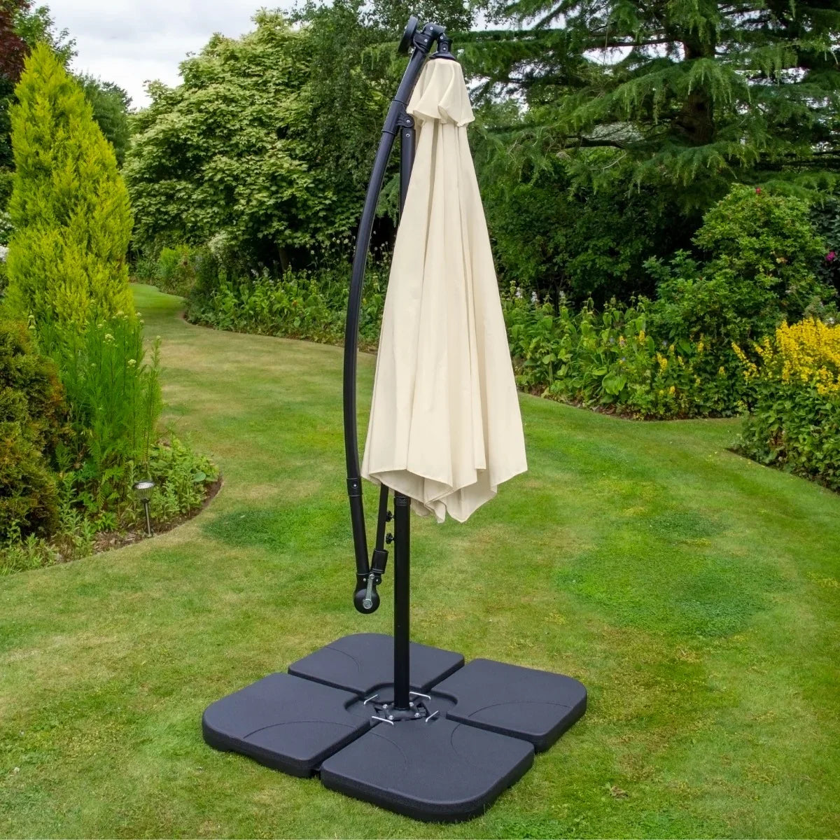 Cream 3m LED cantilever parasol with a sturdy black base, elegantly positioned in a lush garden setting, providing shade and style