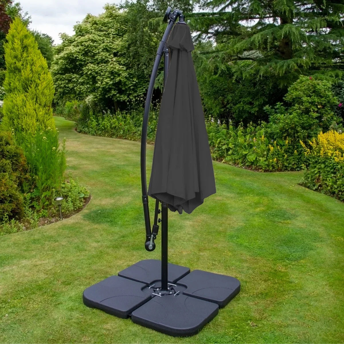 Grey 3m LED cantilever parasol with a sleek fabric canopy, supported by a sturdy black base, set in a lush garden environment