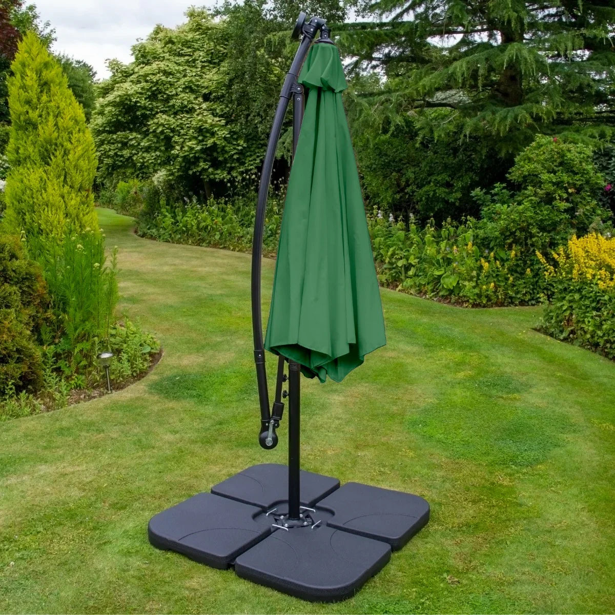 Green 3m LED cantilever parasol with a sleek black base, set in a lush garden, providing shade and style for outdoor spaces
