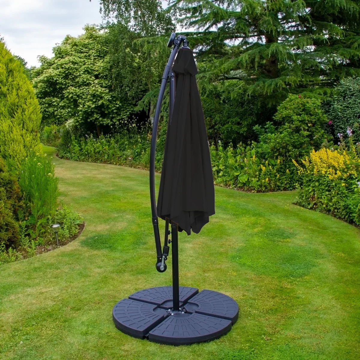 Black 3m cantilever parasol with a sturdy fan base, featuring a sleek design, set in a lush garden with vibrant greenery