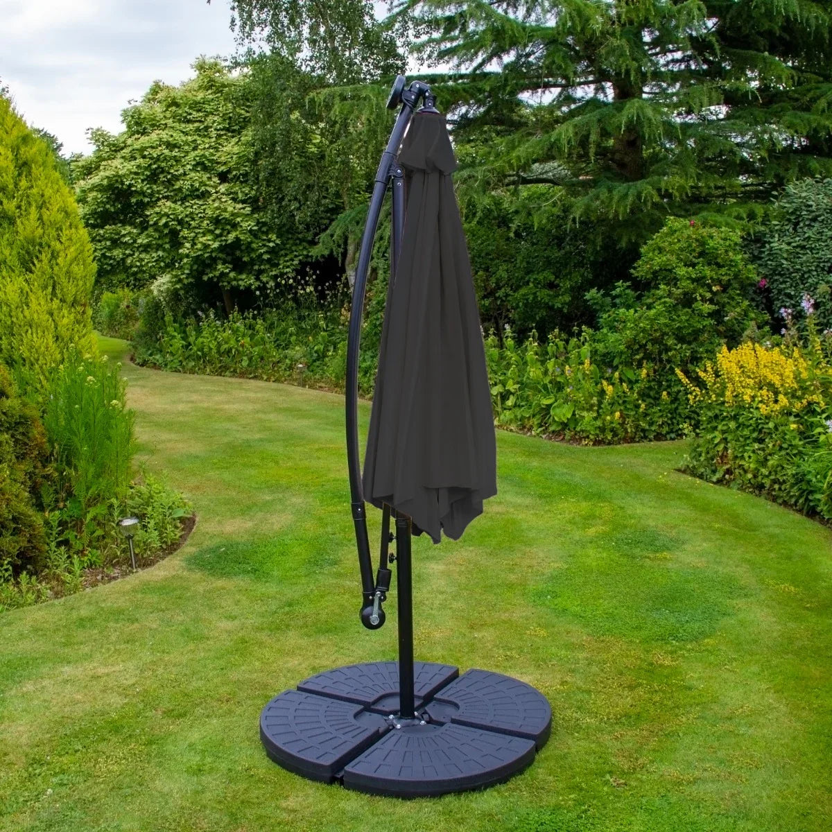 Grey 3m LED cantilever parasol with a sturdy fan base, set in a lush garden, featuring a sleek, modern design and fabric canopy