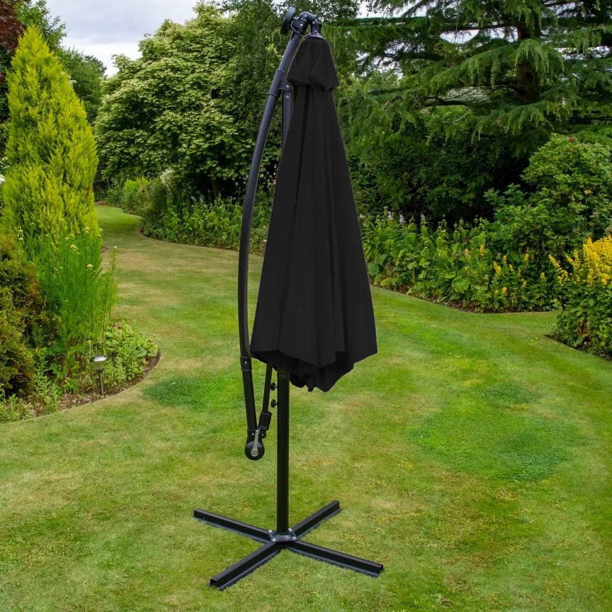 Black 3m LED cantilever parasol with a sleek design, featuring a sturdy base and a fabric canopy, set in a lush garden backdrop