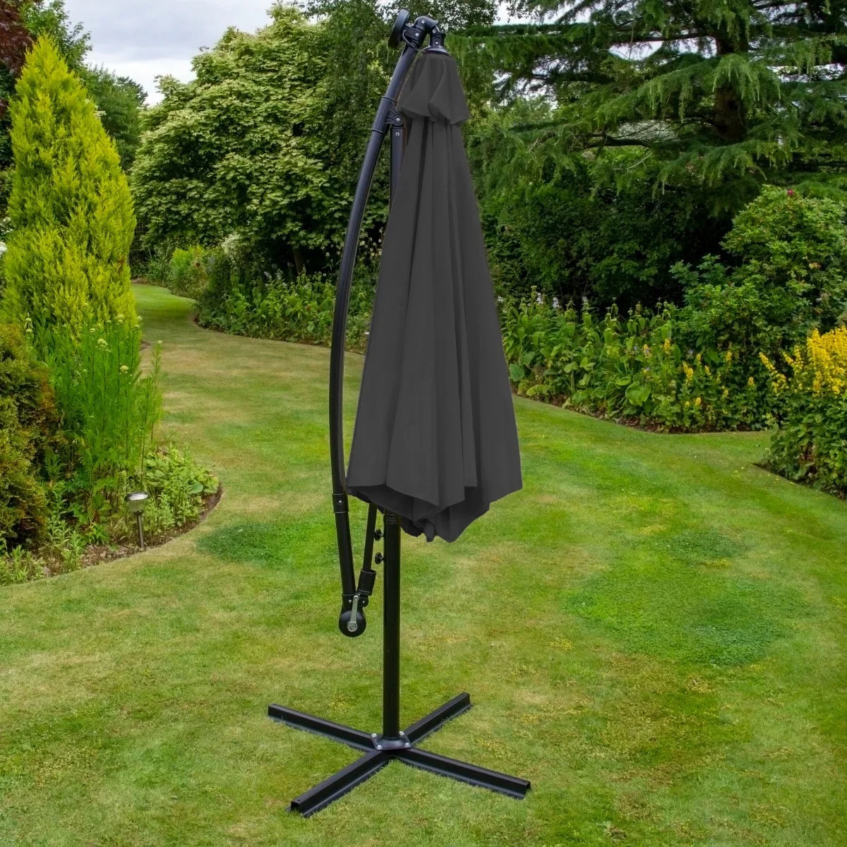 Grey 3m LED cantilever parasol with a sleek curved frame and a dark canopy, set in a lush garden with greenery and grass
