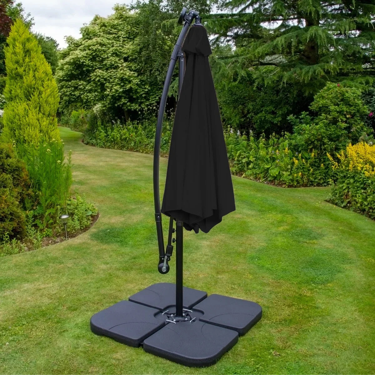 Black 3m LED cantilever parasol with a plain base, featuring a sleek design and fabric canopy, set in a lush garden environment