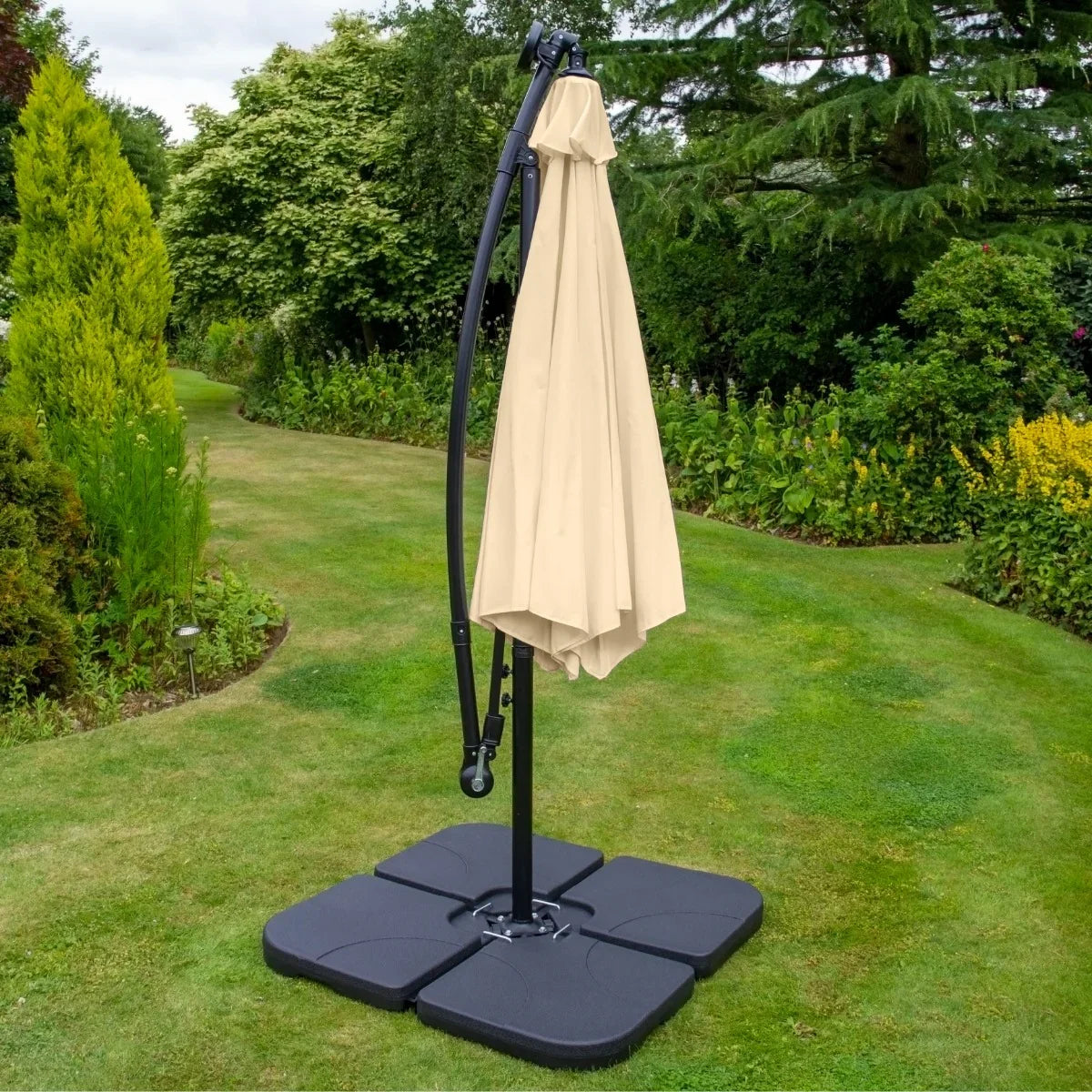 Beige 3m LED cantilever parasol with a plain black base, elegantly positioned in a lush garden setting, providing shade and style