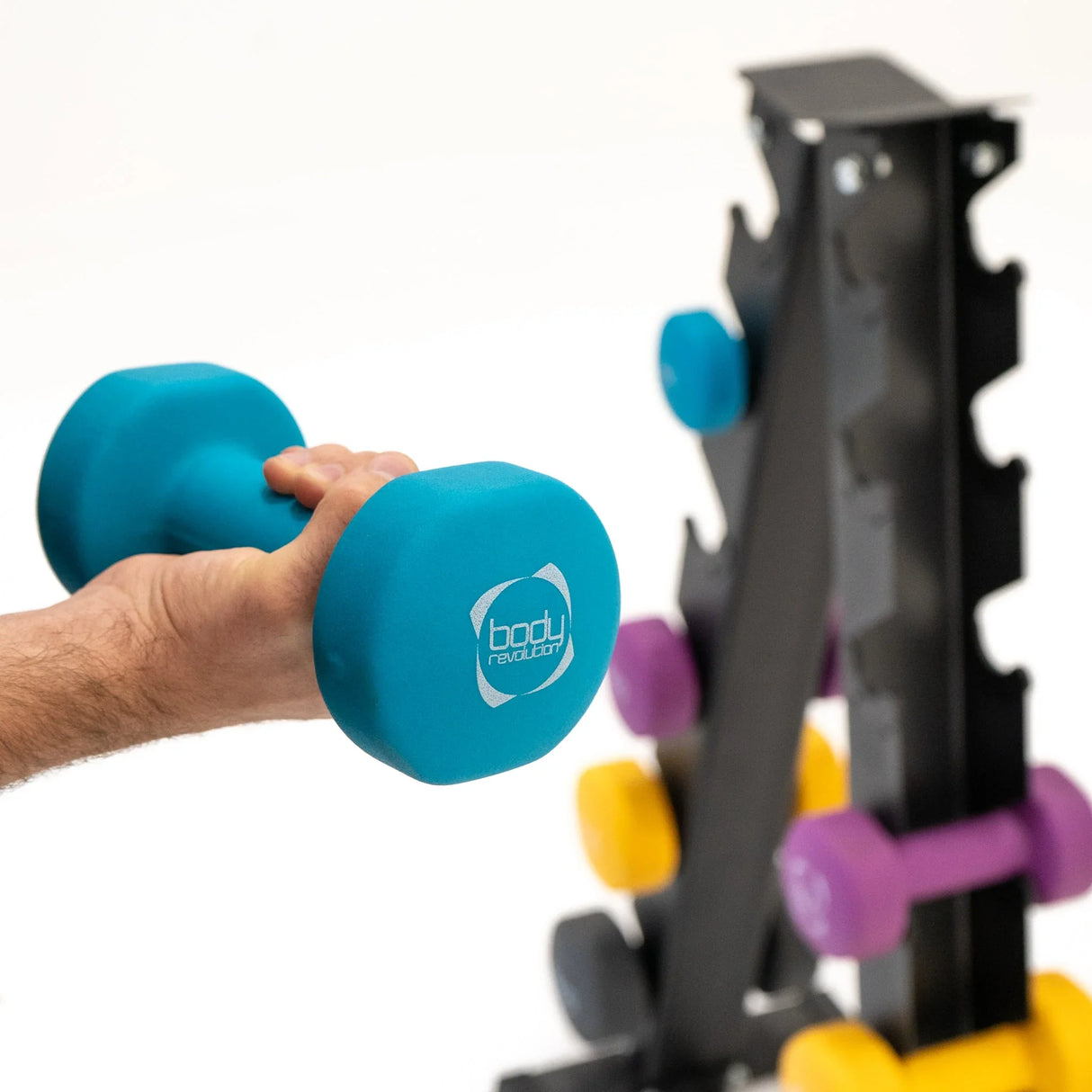 Neoprene dumbbell in vibrant blue held by a hand, with a black rack displaying colorful weights in purple and yellow