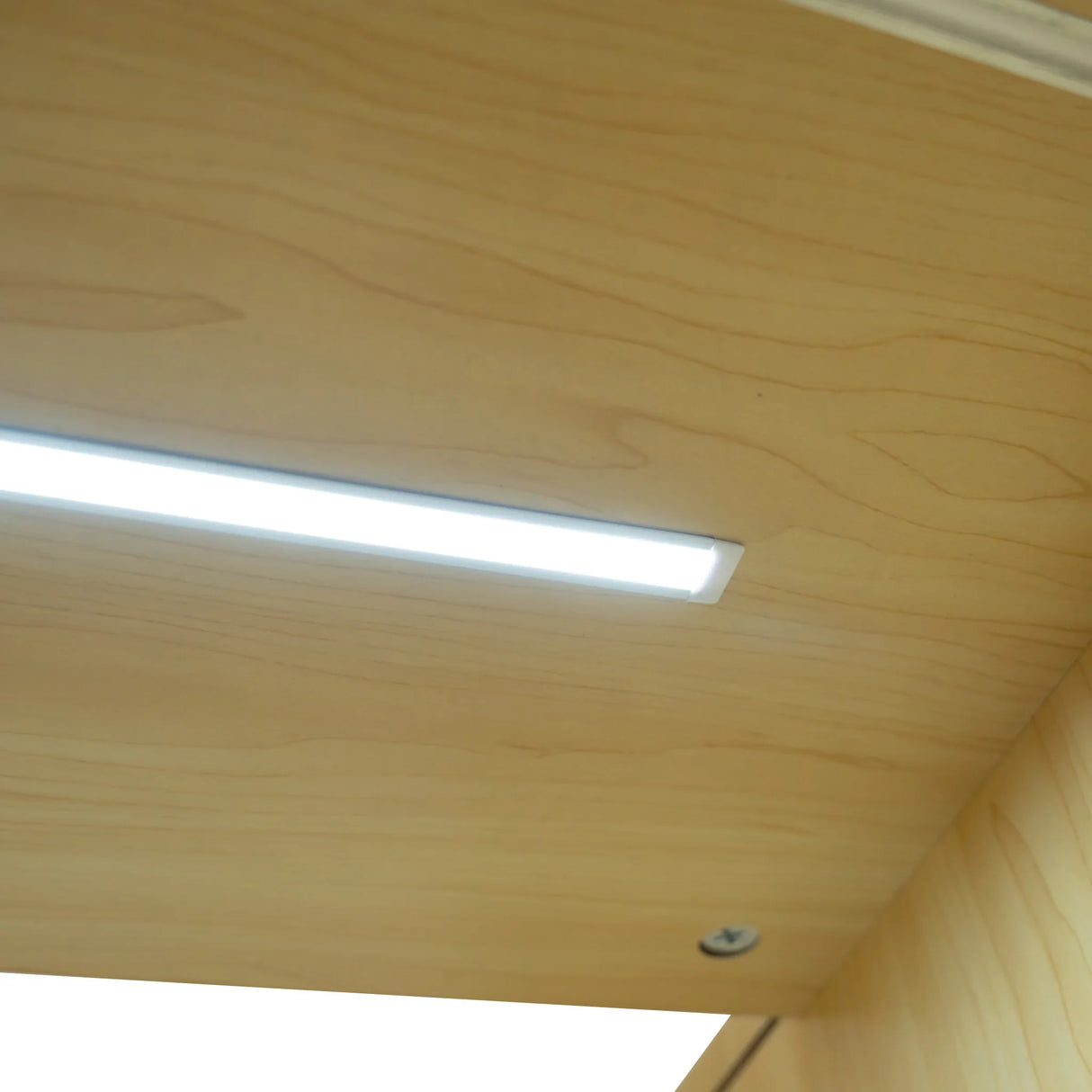 Bright LED light strip mounted under a smooth maple countertop, enhancing visibility and modern aesthetics of the Harmonia shop counter set