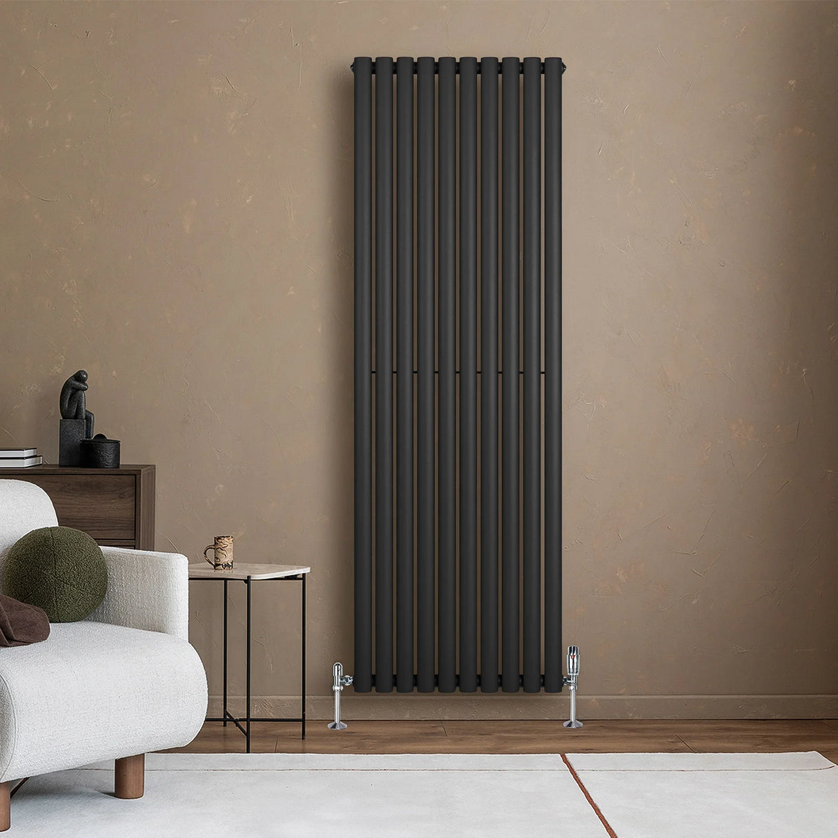 Sleek black oval single column radiator mounted on a textured beige wall, complemented by modern valves and minimalistic decor