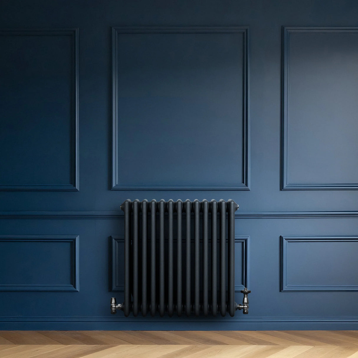 Anthracite grey traditional 4 column radiator mounted on a deep blue wall, featuring sleek valves and a smooth, modern finish