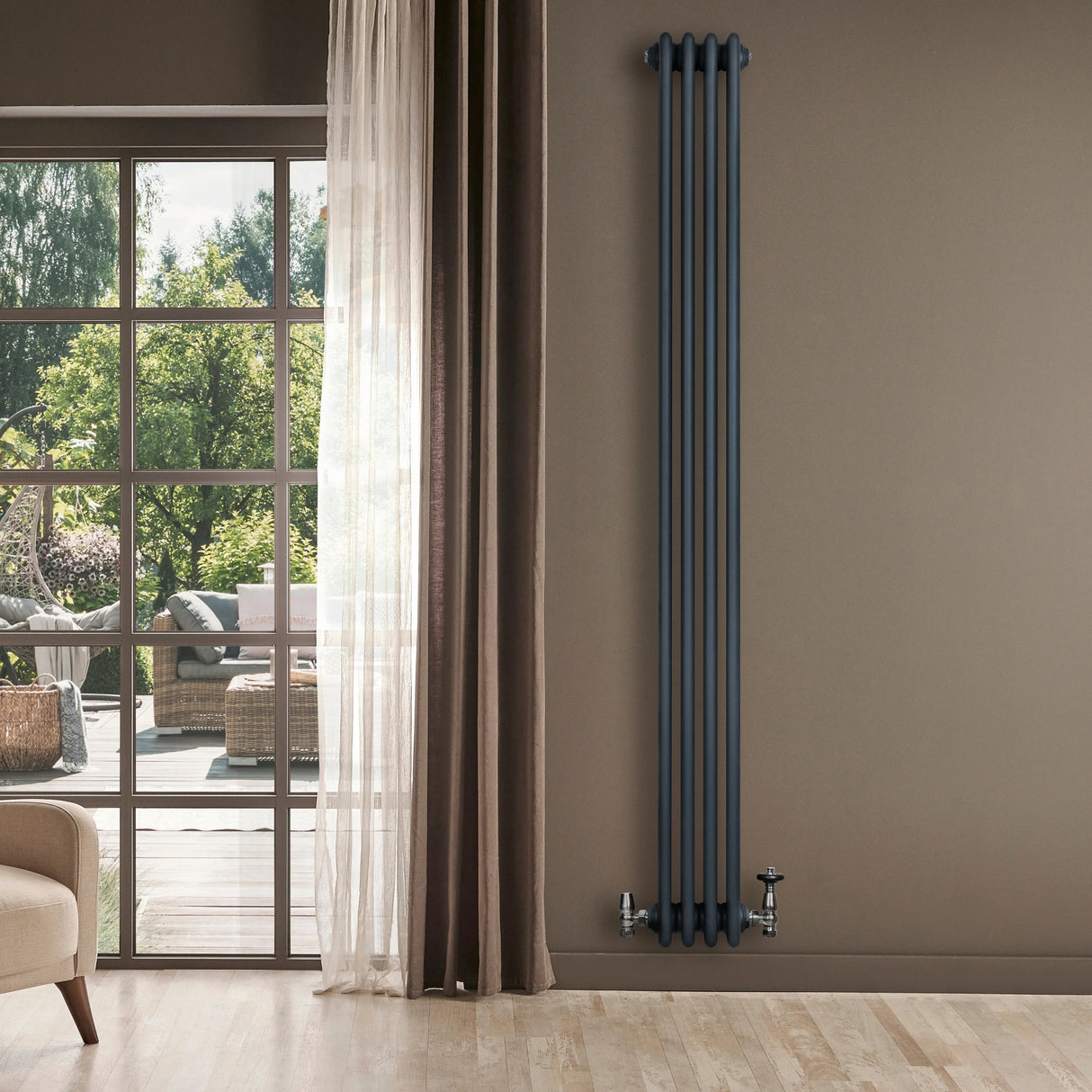 Traditional anthracite grey 4 column radiator with valves, standing against a wall near a large window with natural light