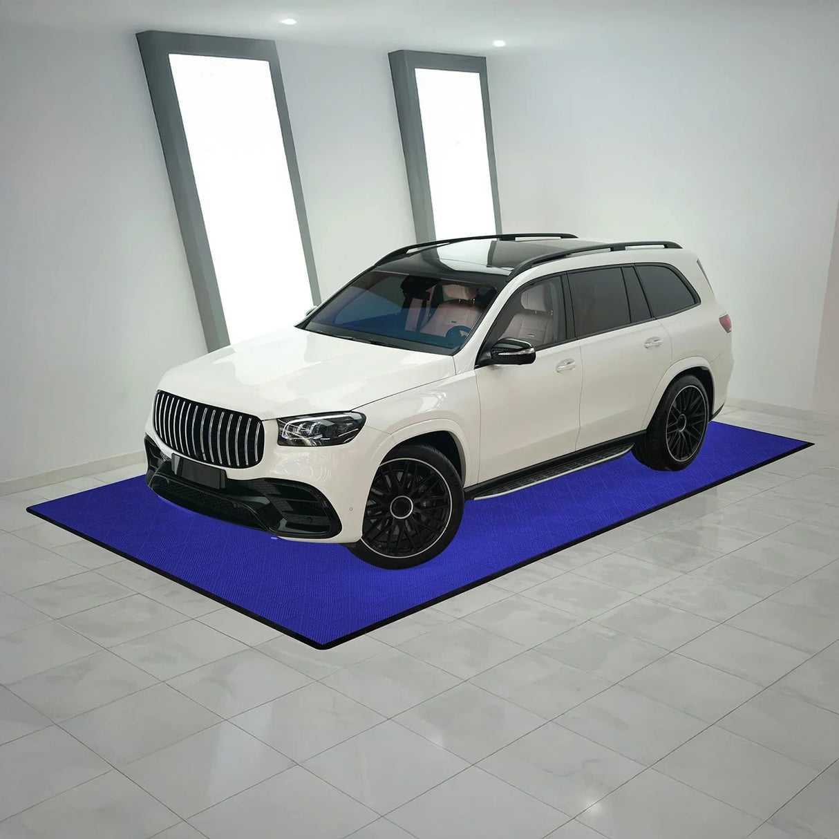 Vented blue garage floor tiles arranged under a white SUV, showcasing a textured surface and sleek edges in a modern setting