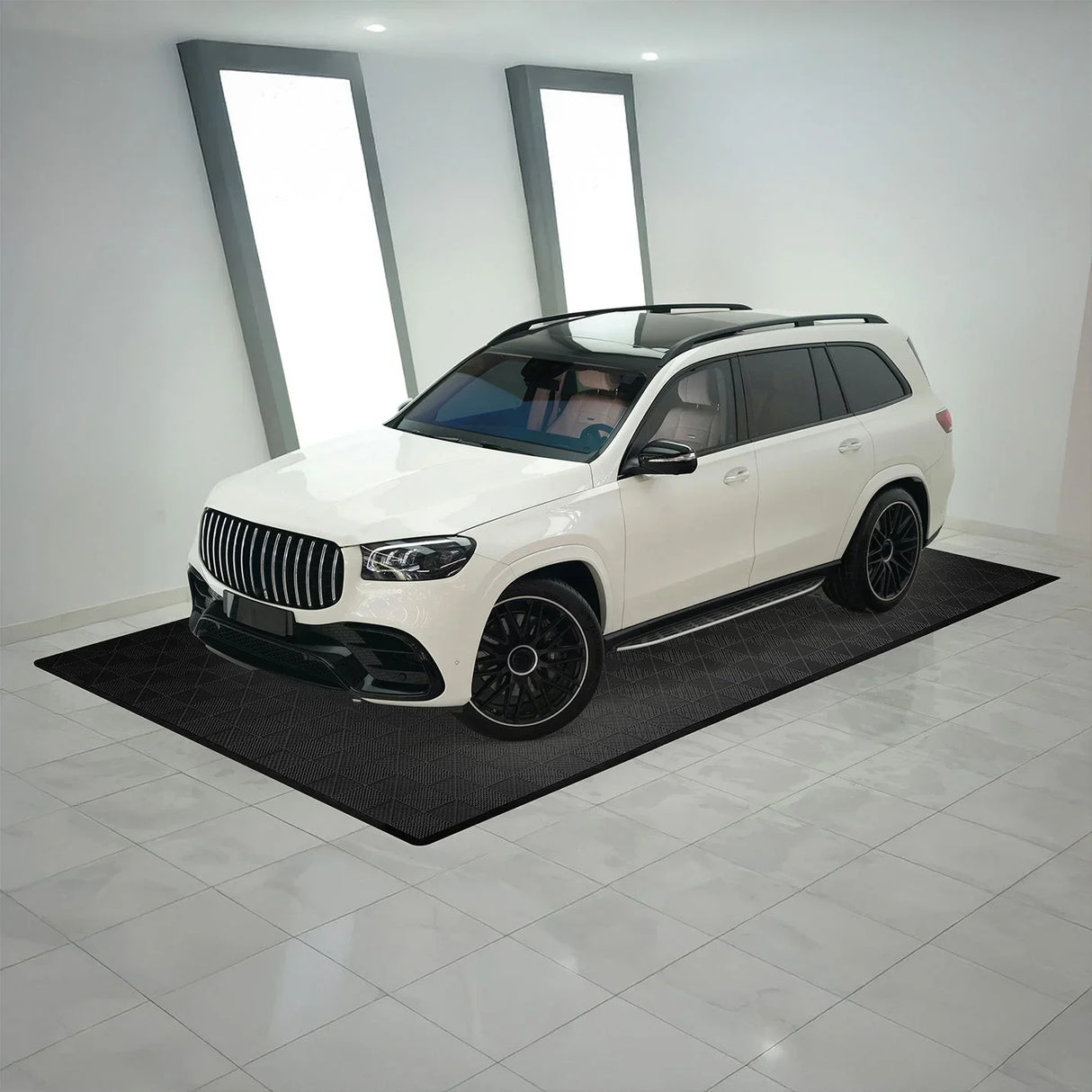 Black vented garage floor tiles arranged neatly under a sleek white SUV, showcasing a textured, durable surface ideal for garages