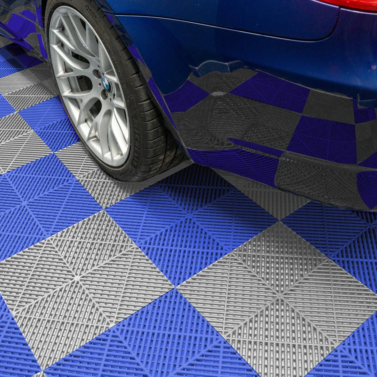 Hexagon LED lights illuminate a garage with blue and grey vented floor tiles, showcasing a sleek car on the textured surface
