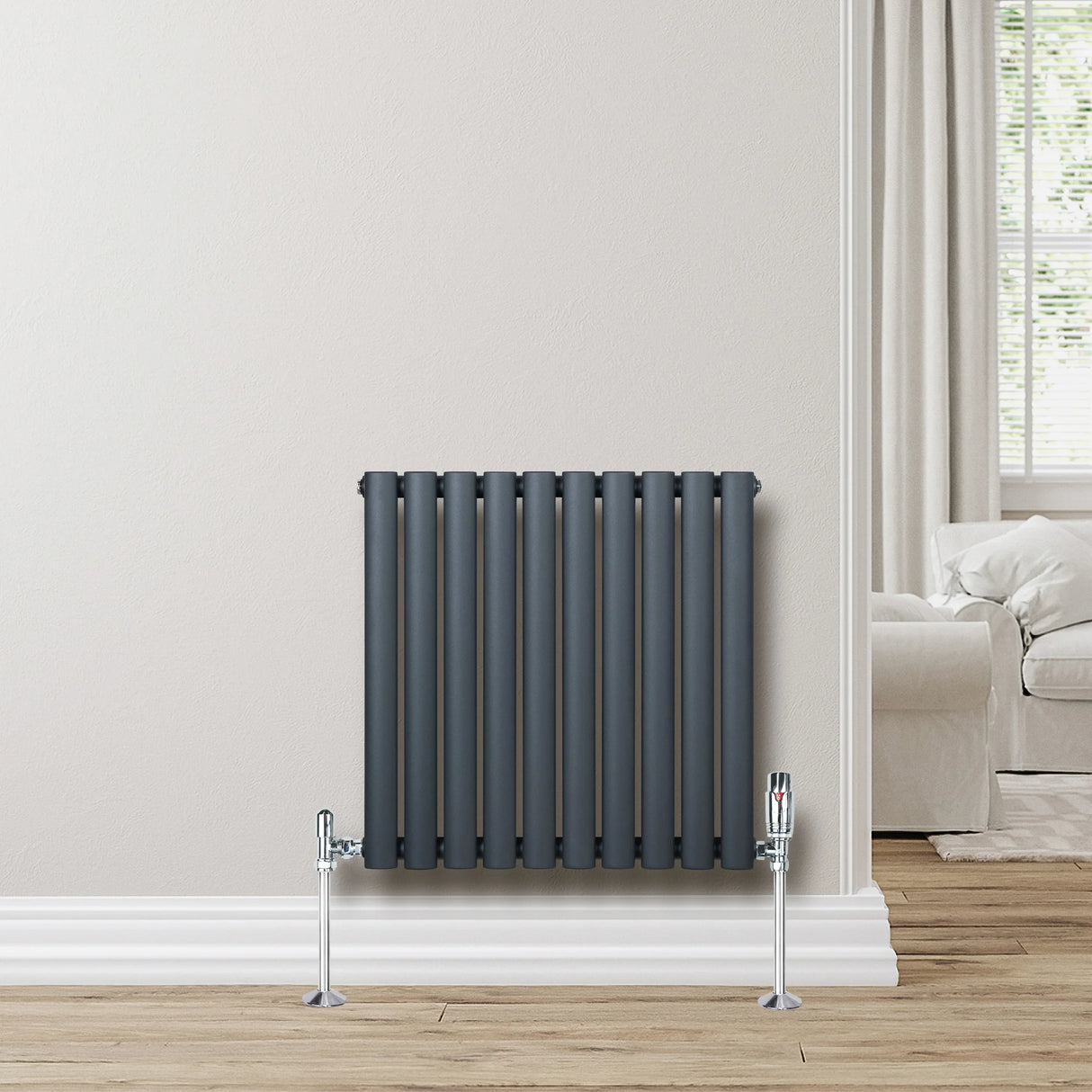 Anthracite grey oval single column radiator, 600 x 600mm, featuring sleek vertical lines and chrome valves against a light wall