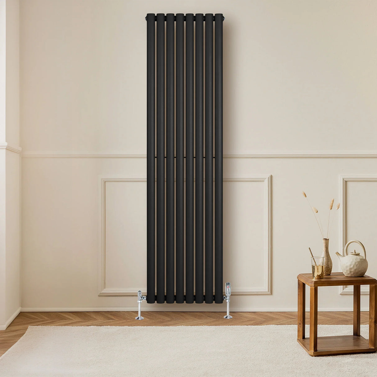Sleek black oval single column radiator, 1800 x 480mm, mounted on a light wall, complementing a wooden table and decor elements