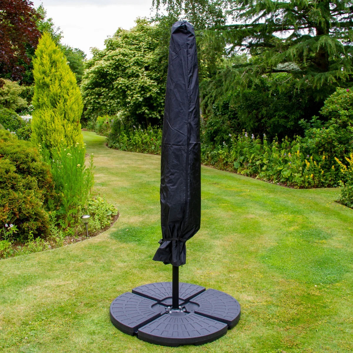 Cream 3m LED cantilever parasol with a sturdy fan base, covered in a protective black cover, set in a lush garden backdrop