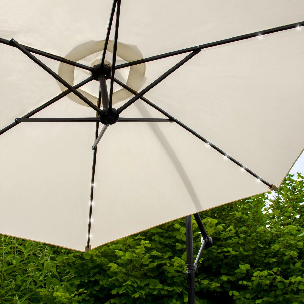 Cream 3m LED cantilever parasol with a sturdy black frame, featuring soft fabric and integrated LED lights for evening ambiance