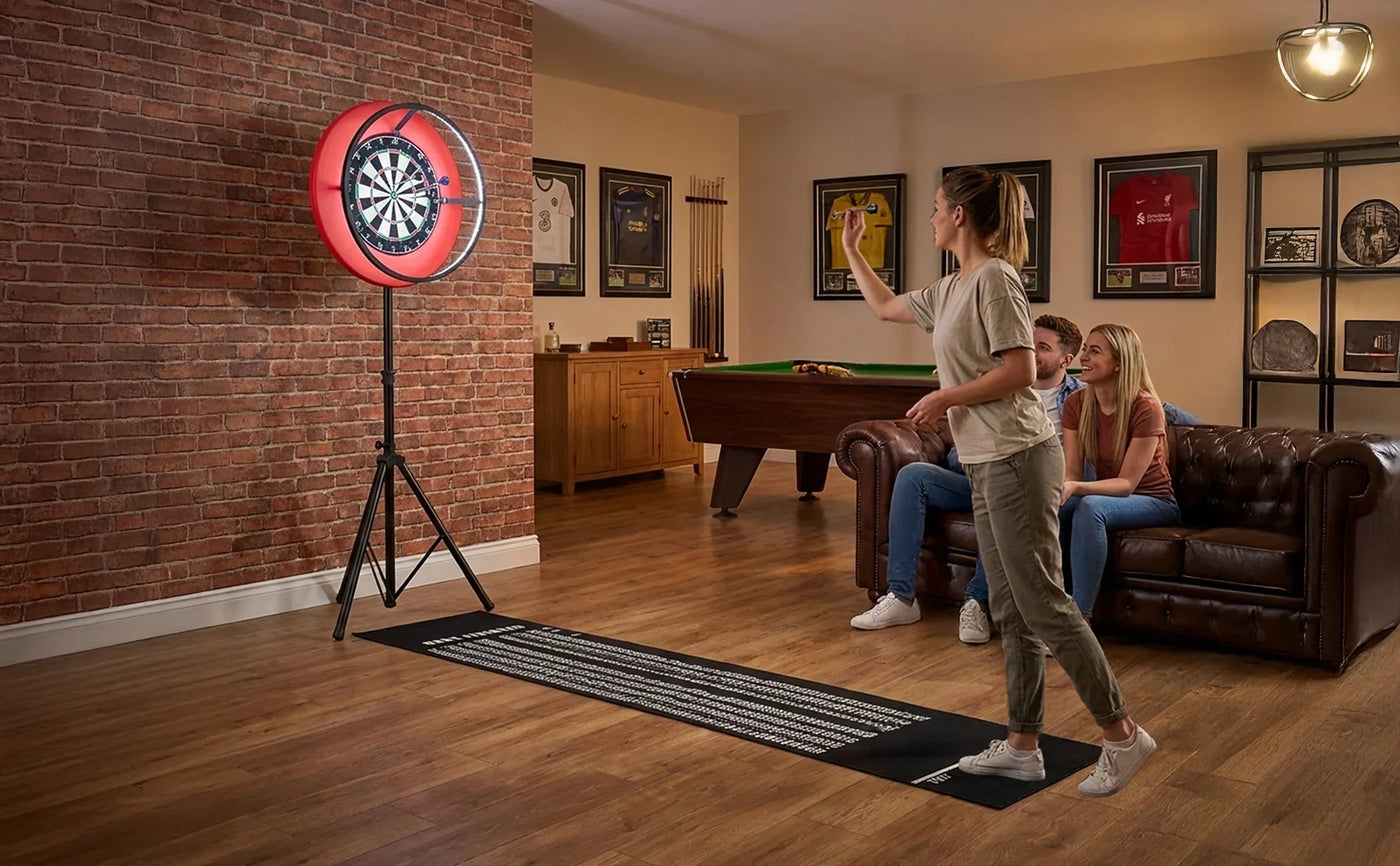 A woman throws a dart at a red and black dartboard in a cozy game room with a brick wall, leather couch, and pool table