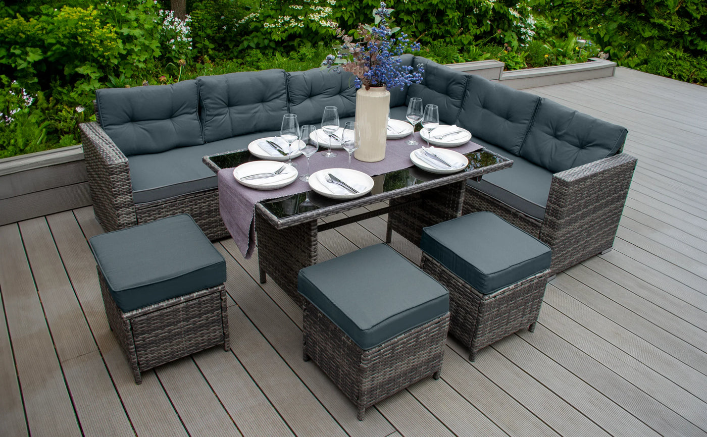 Stylish outdoor sectional sofa set with gray cushions, a glass-top table, and decorative vase, surrounded by lush greenery