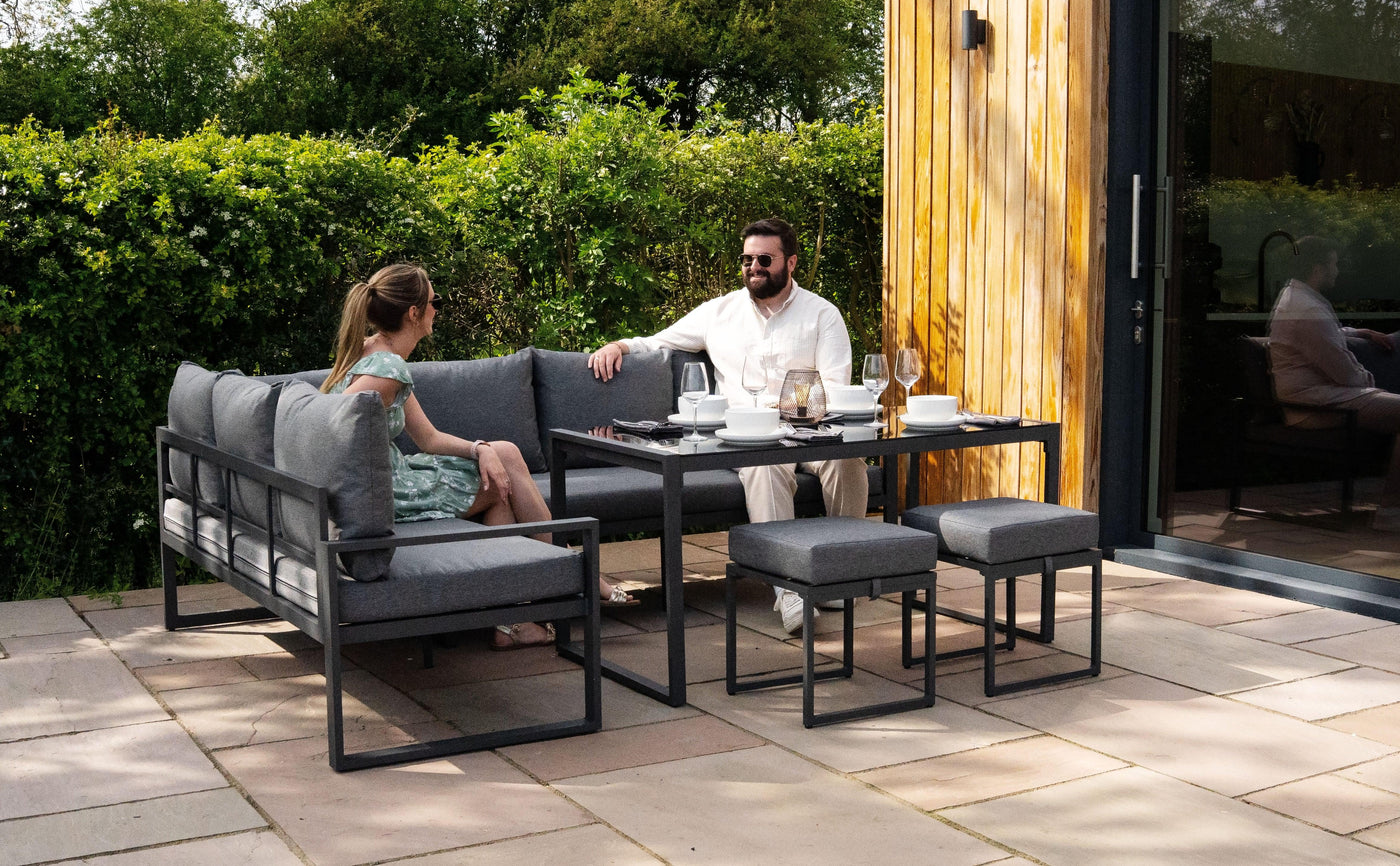 Stylish outdoor dining set featuring gray cushions, a sleek metal frame, and a modern table, set in a lush garden setting
