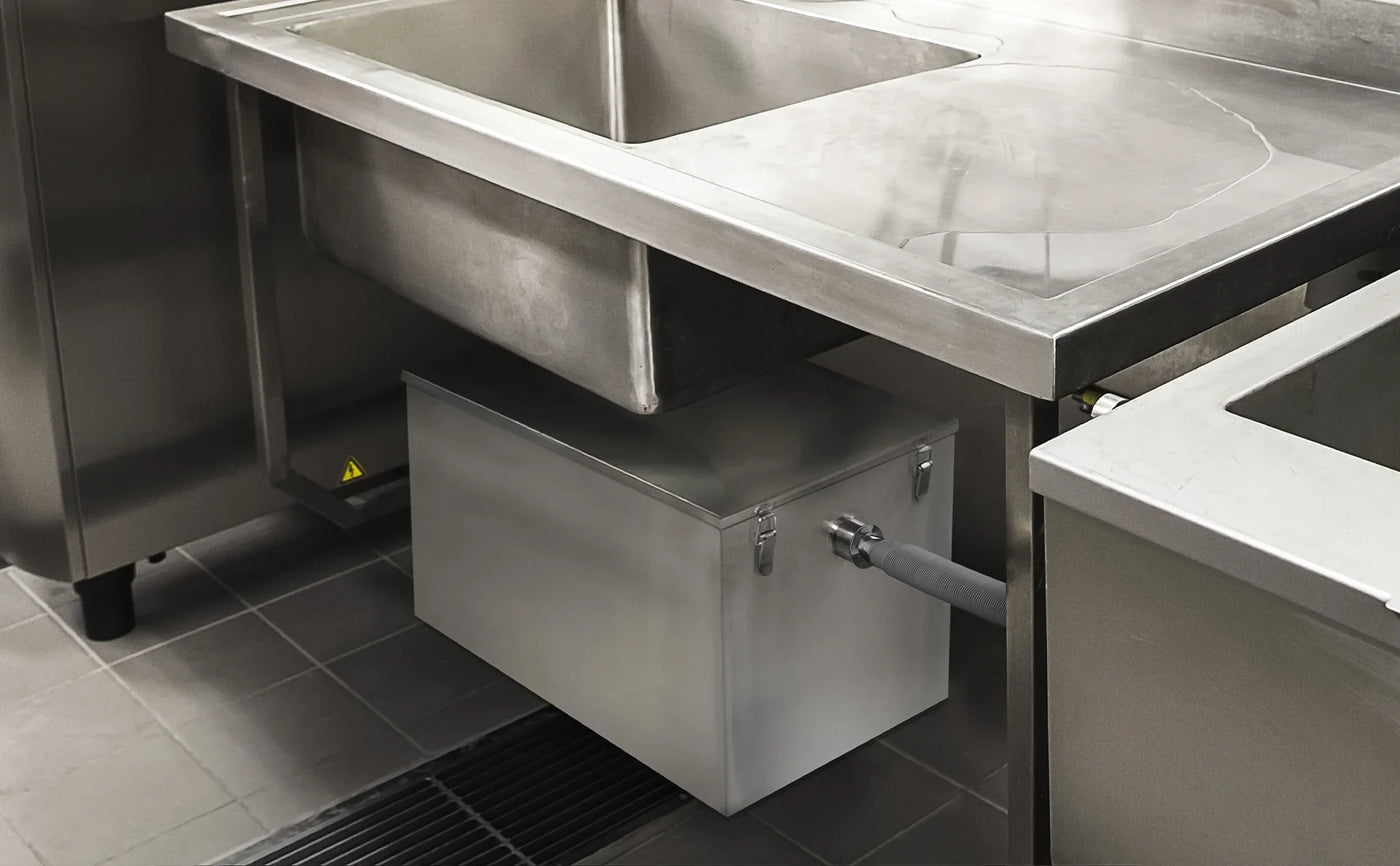 Stainless steel kitchen sink with a sleek, modern design, featuring a connected waste container underneath for efficient disposal