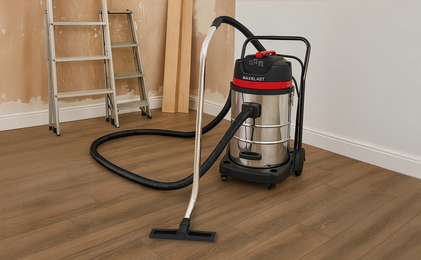 Stainless steel wet/dry vacuum cleaner with a red and black design, flexible hose, and floor attachment on wooden flooring