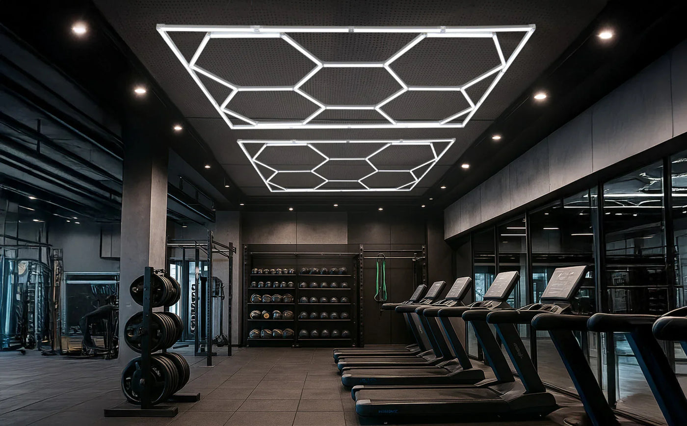 Modern gym interior featuring hexagonal LED ceiling lights, sleek black walls, treadmills, and weightlifting equipment in a spacious layout