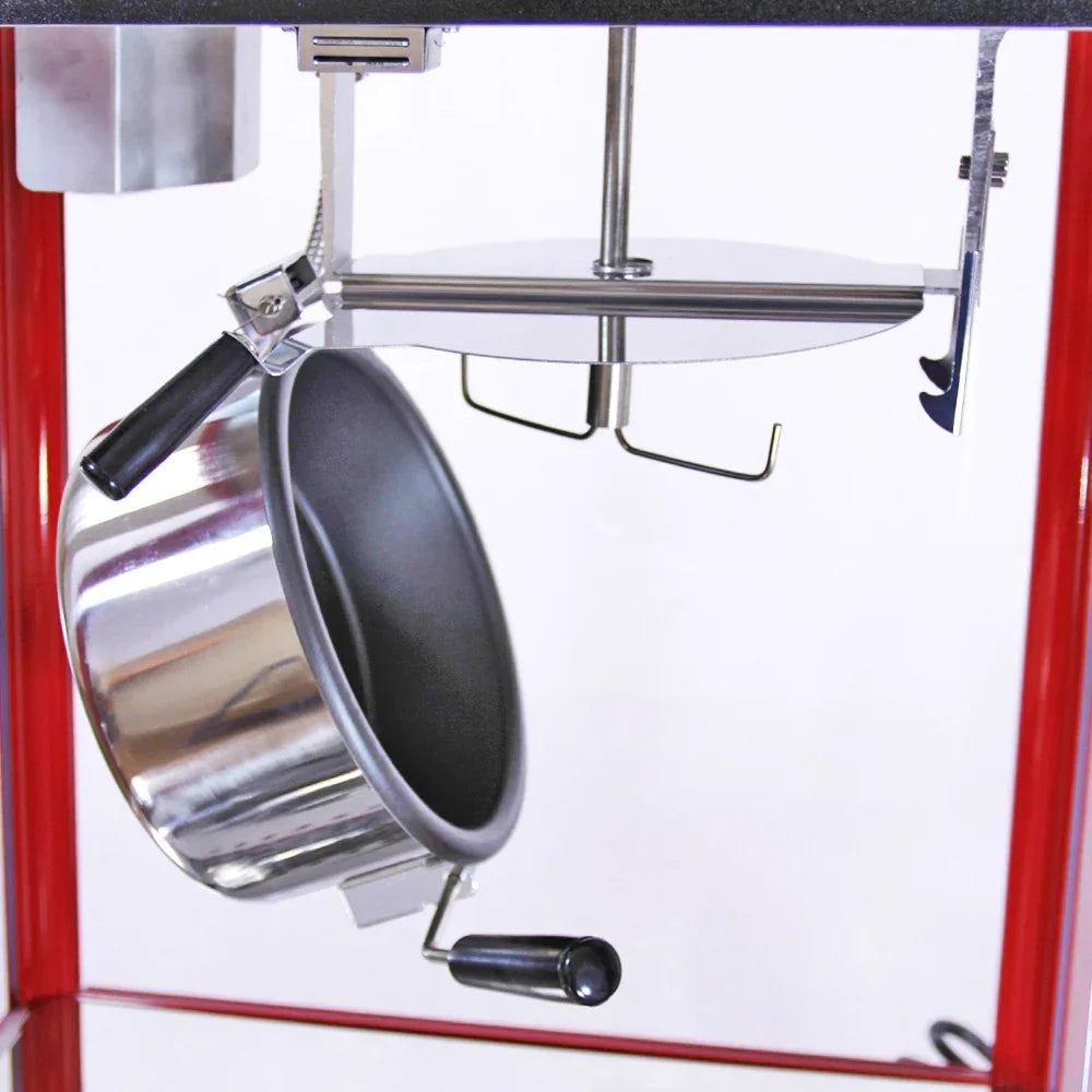 Stainless steel kettle with a black handle hanging from a red popcorn cart, showcasing the machine's interior components