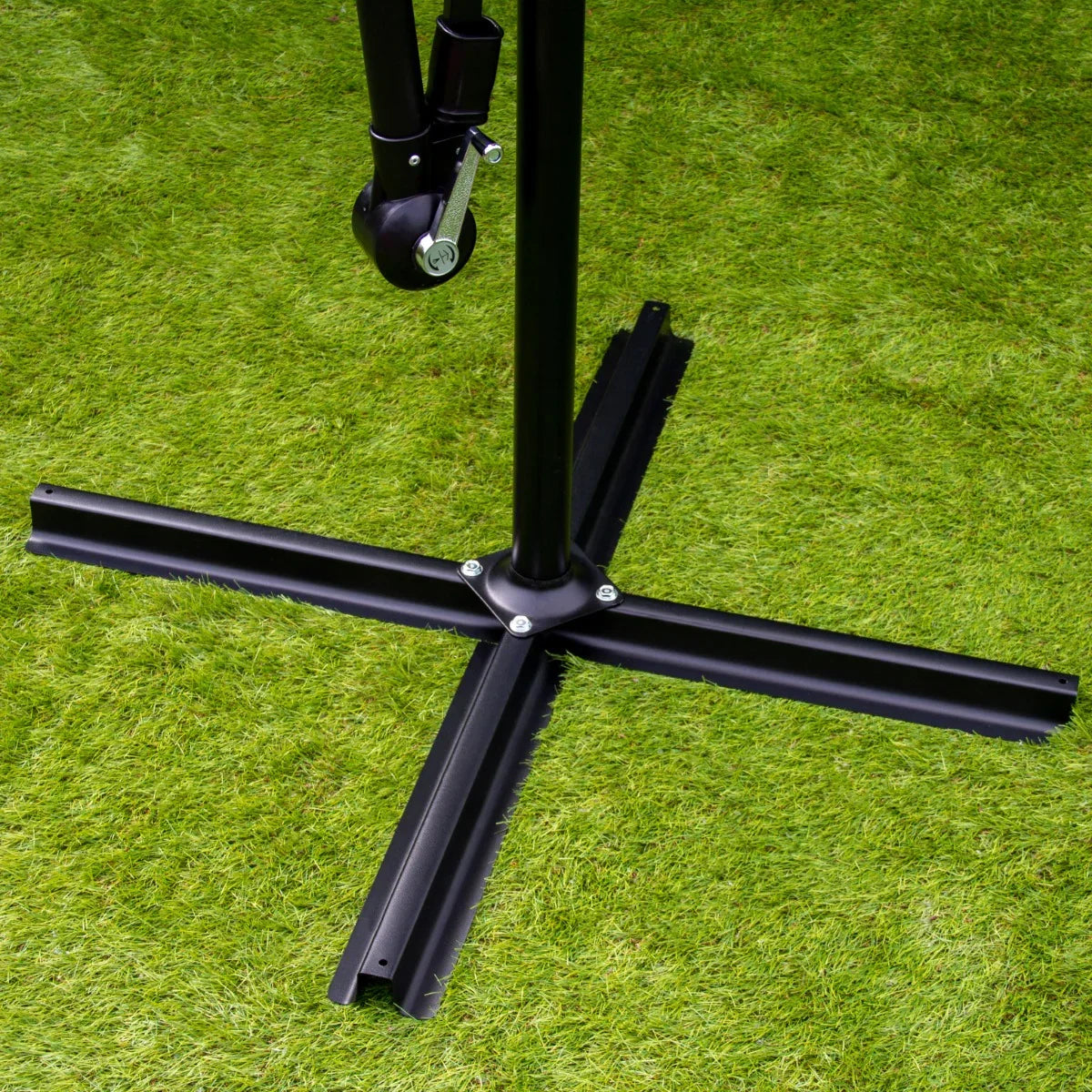 Black cross base of a green 3m LED cantilever parasol, featuring sturdy metal construction and a sleek, modern design on grass