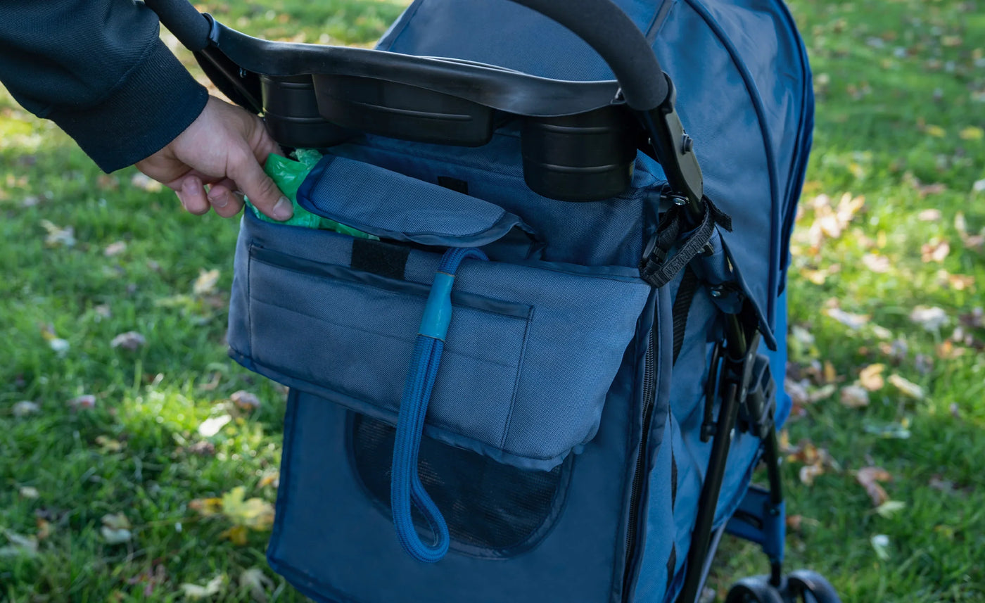 A person reaching into a blue stroller's storage pocket, showcasing its spacious design and practical organization features