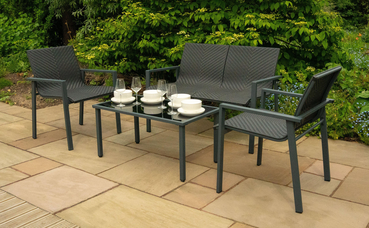 Stylish outdoor seating set featuring two woven chairs and a glass-top table, elegantly arranged with white dishware and glasses