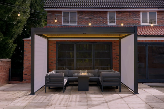 Stylish outdoor seating area featuring a modern grey sectional sofa, sleek coffee table, and cozy lighting under a pergola