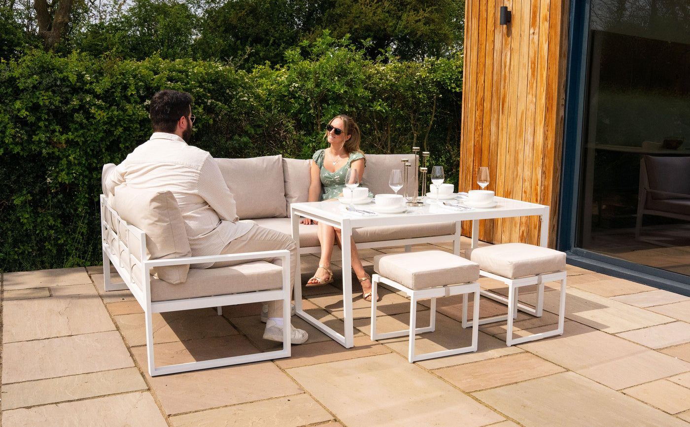 Stylish outdoor seating area with a white metal frame, plush cushions, and a glass-top table, perfect for relaxing gatherings