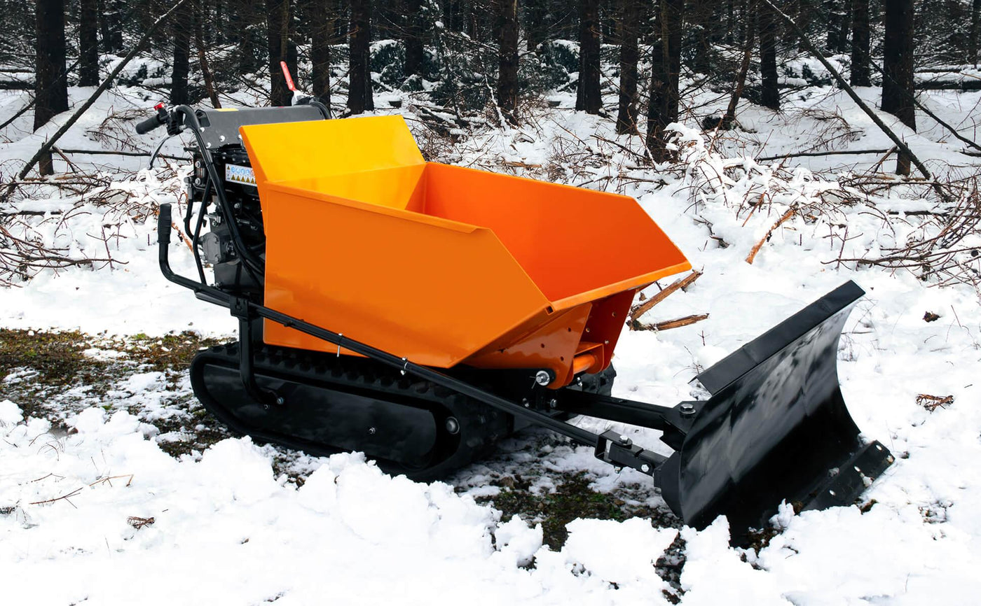 Compact snow plow with a bright orange hopper and black blade, set against a snowy forest backdrop with scattered branches