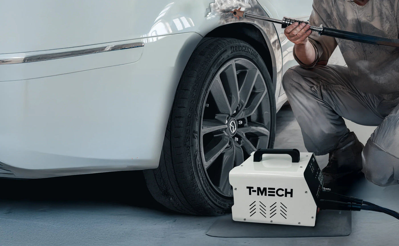 A person using a T-MECH pressure washer on a white car tire, showcasing the sleek black tire and modern equipment on a clean surface