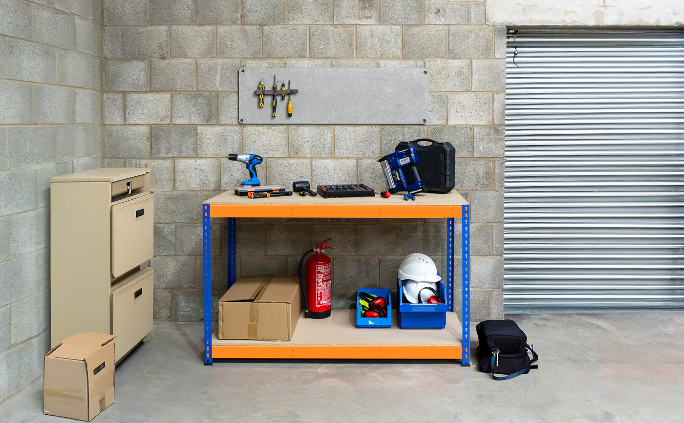 A well-organized workshop featuring a sturdy orange shelf with tools, storage boxes, safety gear, and a filing cabinet against a concrete wall