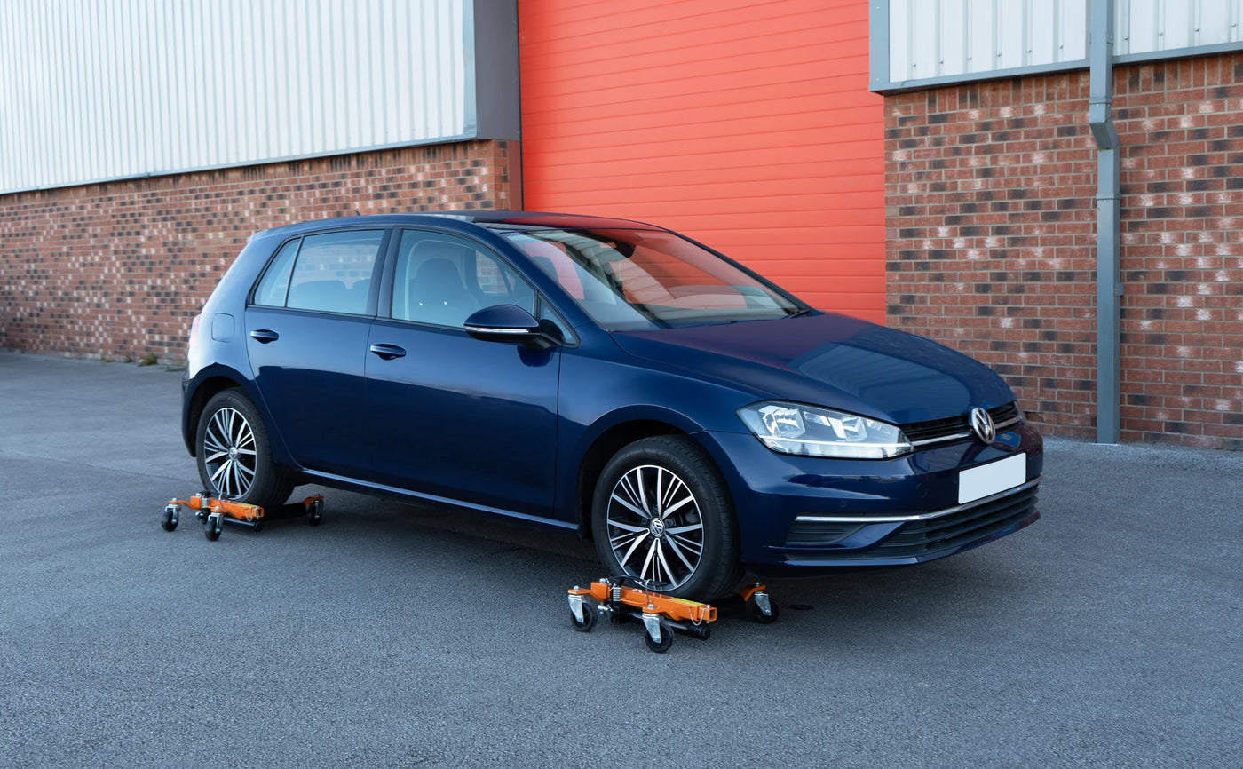 Blue Volkswagen Golf parked on a smooth surface, featuring sleek lines, alloy wheels, and orange wheel dollies for easy movement