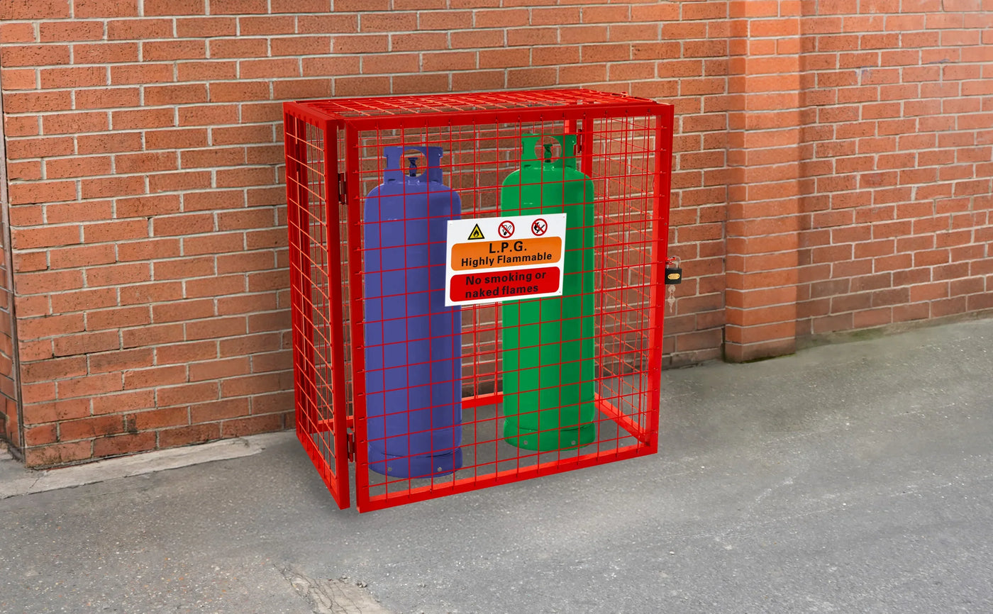 Red metal cage containing blue and green gas cylinders, with a warning sign indicating flammability, against a brick wall